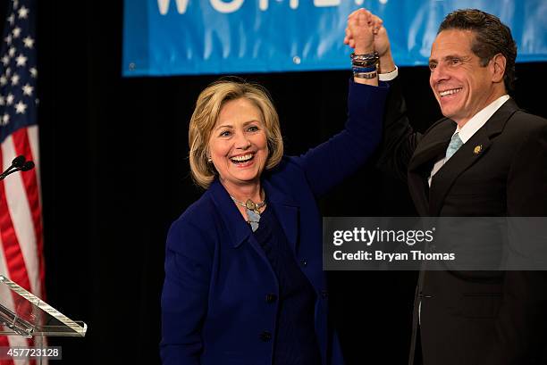 Former U.S. Secretary of State and U.S. Sen. Hillary Rodham Clinton raises the hand of incumbent New York Governor Andrew Cuomo laugh during a "Women...