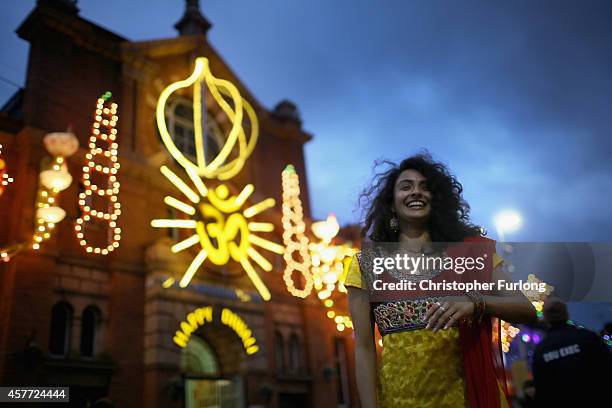 Kelly Vaduka laughs as friends photograph her in front of illuminations as she celebrates the Hindu festival of Diwali on October 23, 2014 in...