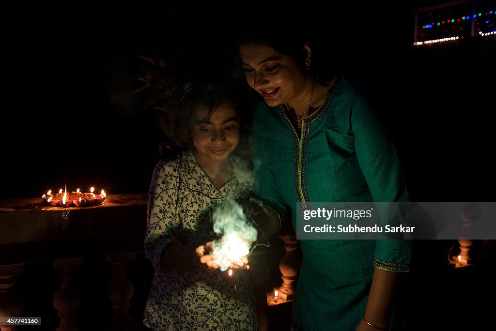 An Indian woman and her daughter burn firework on DIwali.