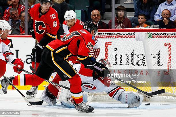Sean Monahan of the Calgary Flames scores on a backhand against Cam Ward of the Carolina Hurricanes at Scotiabank Saddledome on October 23, 2014 in...