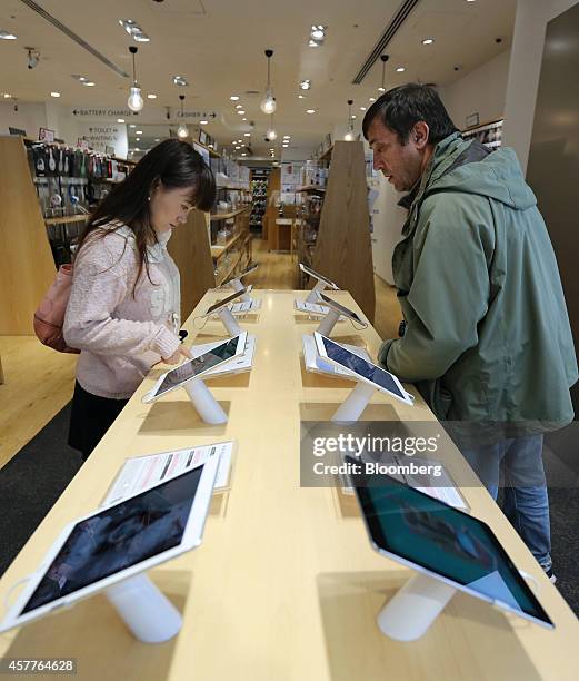 Customers look at Apple Inc.'s new iPad Air 2 and iPad Mini 3 tablets displayed at a SoftBank Corp. Store in the Ginza district of Tokyo, Japan, on...