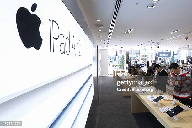 Customers look at Apple Inc.'s new iPad Air 2 and iPad Mini 3 tablets displayed at a SoftBank Corp. Store in the Ginza district of Tokyo, Japan, on...