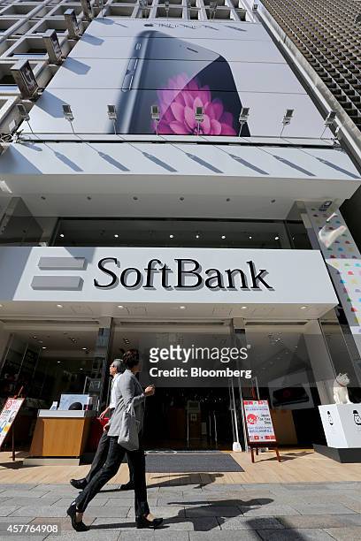 Pedestrians walk past a SoftBank Corp. Store in the Ginza district during the sales launch of Apple Inc.'s new iPad Air 2 and iPad Mini 3 tablets in...
