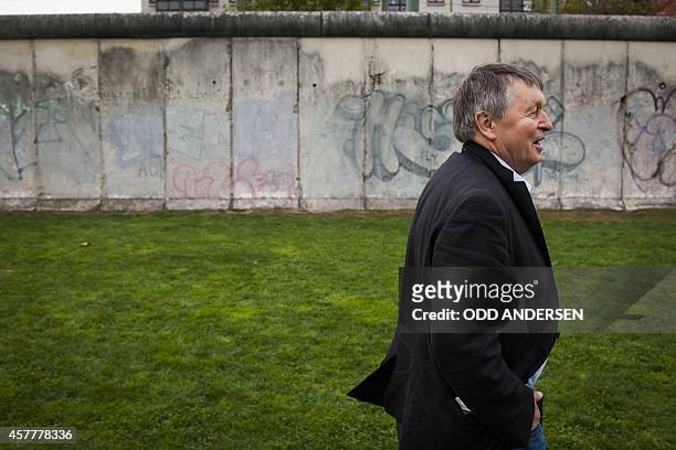 Hartmut Richter poses for pictures along remains of the 'Wall' along Bernauer strasse in Berlin on October 8, 2014. Richter fled the communist German...