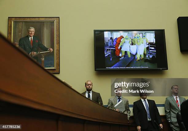 People dressed in Hazmat suits dealing with Ebola patients are shown on a monitor during a House Oversight and Government Reform Committee hearing on...