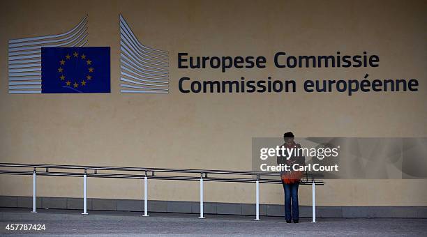 Woman checks her phone by a sign on the European Commission building on October 24, 2014 in Brussels, Belgium. Alongside criticism from outgoing...