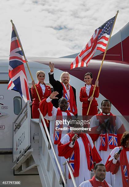 Richard Branson, chairman and founder of Virgin Group Ltd., center, waves while exiting a Boeing Co. 787 Dreamliner with Virgin Atlantic Airways Ltd....