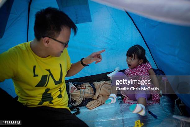 Pro-democracy activist Oscar Lee, jokes around with his three year old daughter Annecy in their tent on the street outside the Hong Kong's Government...