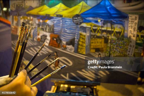 Painter Perry Dino works on his 13th oil painting depicting the protest at the main protest as a festival atmosphere prevails October 25, 2014 in...