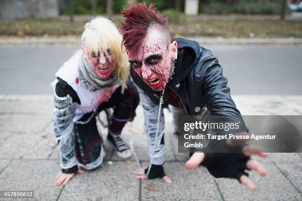 Two zombie enthusiast crawl over the Alexanderplatz as part of a flashmob on October 25, 2014 in Berlin, Germany. Over 150 participants dressed as...