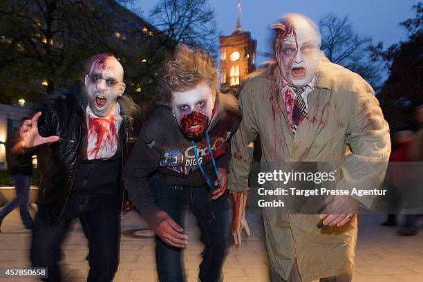 Three zombie enthusiasts walk over the Alexanderplatz as part of a flashmob on October 25, 2014 in Berlin, Germany. Over 150 participants dressed as...