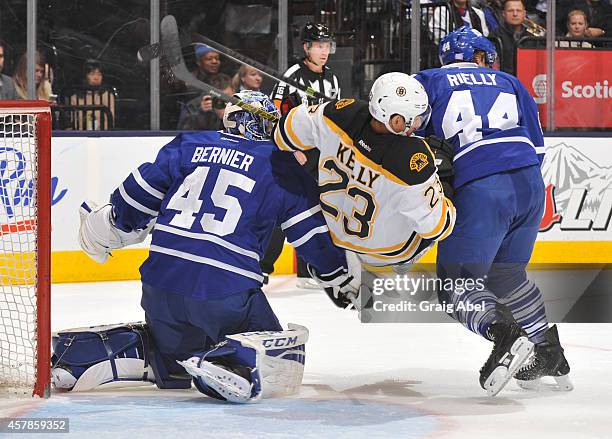 Morgan Rielly of the Toronto Maple Leafs battles with Chris Kelly of the Boston Bruins as teammate Jonathan Bernier defends the goal during NHL game...