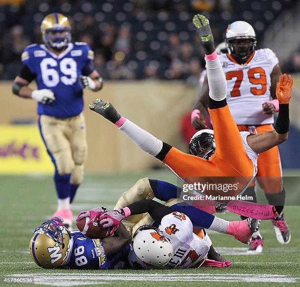 LaRose of the BC Lions flies over Justin Wilson of the Winnipeg Blue Bombers and T.J. Lee in first half action in a CFL game at Investors Group Field...