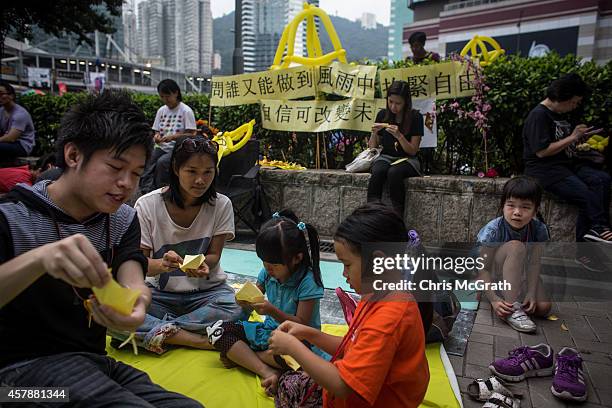 Children are taught how to make small paper umbrellas at an activity corner on a street outside Hong Kong's Government Complex in on October 26, 2014...