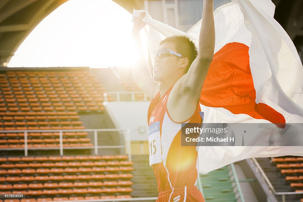 Male athlete holding up Japanese flag