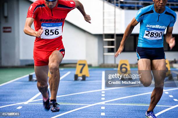 male athletes running on race track - japan racing foto e immagini stock