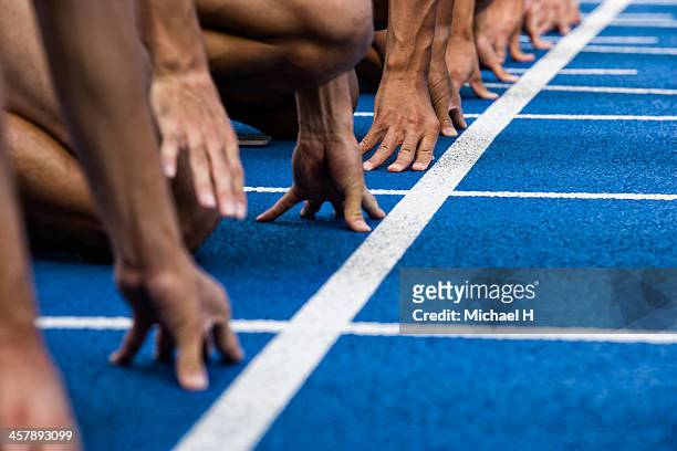 track sprinters lined up at starting - leichtathletik stock-fotos und bilder