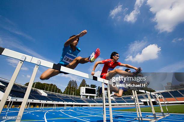male runners jumping hurdles in race - hurdling track event 個照片及圖片檔