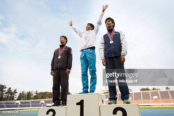 three athletes on podium with medals - siegerpodest stock-fotos und bilder