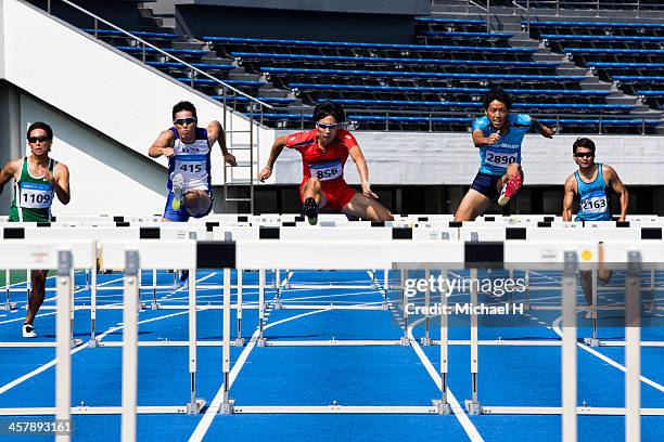 male runners jumping hurdles in race - sprint planning stock pictures, royalty-free photos & images