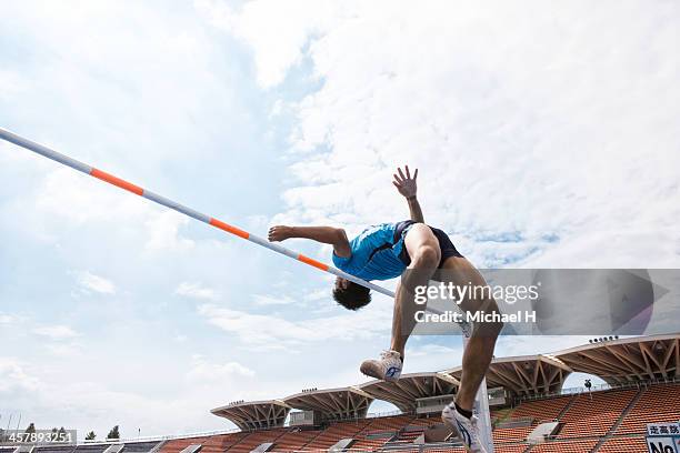 male athlete performing high jump - hochsprung stock-fotos und bilder