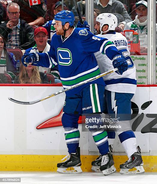 Zack Kassian of the Vancouver Canucks checks Jason Garrison of the Tampa Bay Lightning during their NHL game at Rogers Arena October 18, 2014 in...