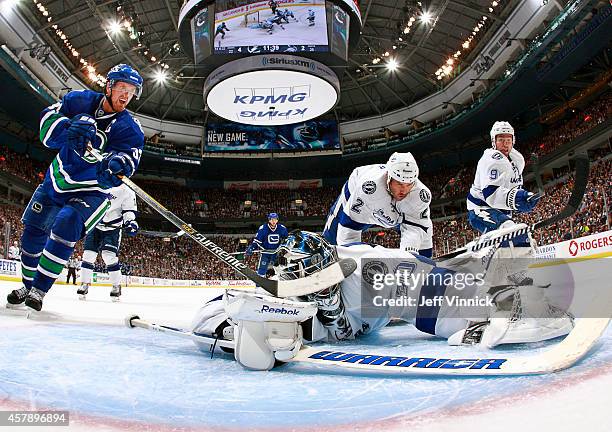 Ben Bishop of the Tampa Bay Lightning makes a save as Henrik Sedin of the Vancouver Canucks looks for a rebound during their NHL game at Rogers Arena...