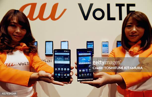 Models hold Japanese mobile communication giant KDDI's new smartphones, 'isai VL' and 'URBANO' for the company's new communication service, "au VoLTE...