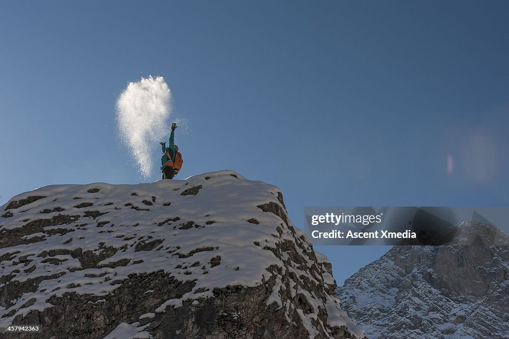 Hiker throws snow overheard from mountain summit