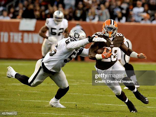 Running back Terrence West of the Cleveland Browns carries the ball around the tackle of linebacker Sio Moore of the Oakland Raiders during a game on...