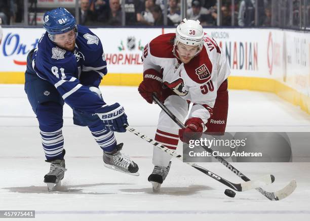 Antoine Vermette of the Phoenix Coyotes skates against Phil Kessel of the Toronto Maple Leafs during an NHL game at the Air Canada Centre on December...