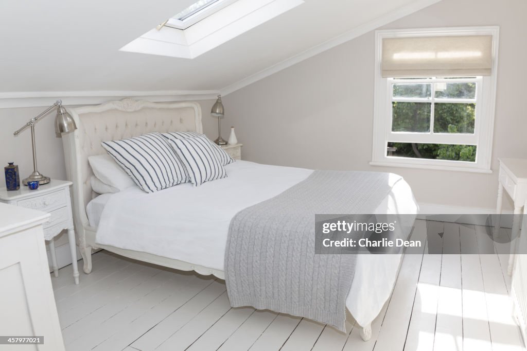 Bed in whitewashed attic bedroom