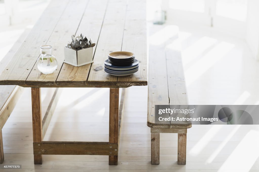 Plates and silverware stacked on wooden table