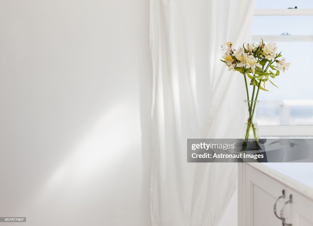 Vase of flowers on desk in white room