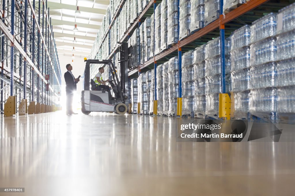 Workers with forklift in bottling warehouse.