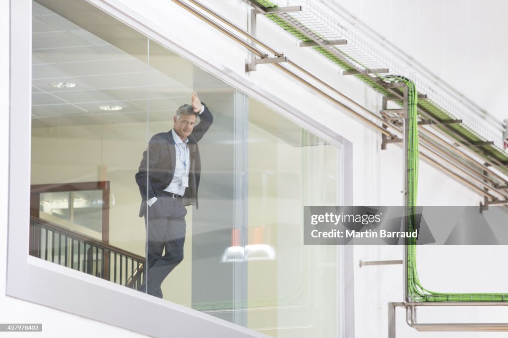 Supervisor leaning on glass window in warehouse