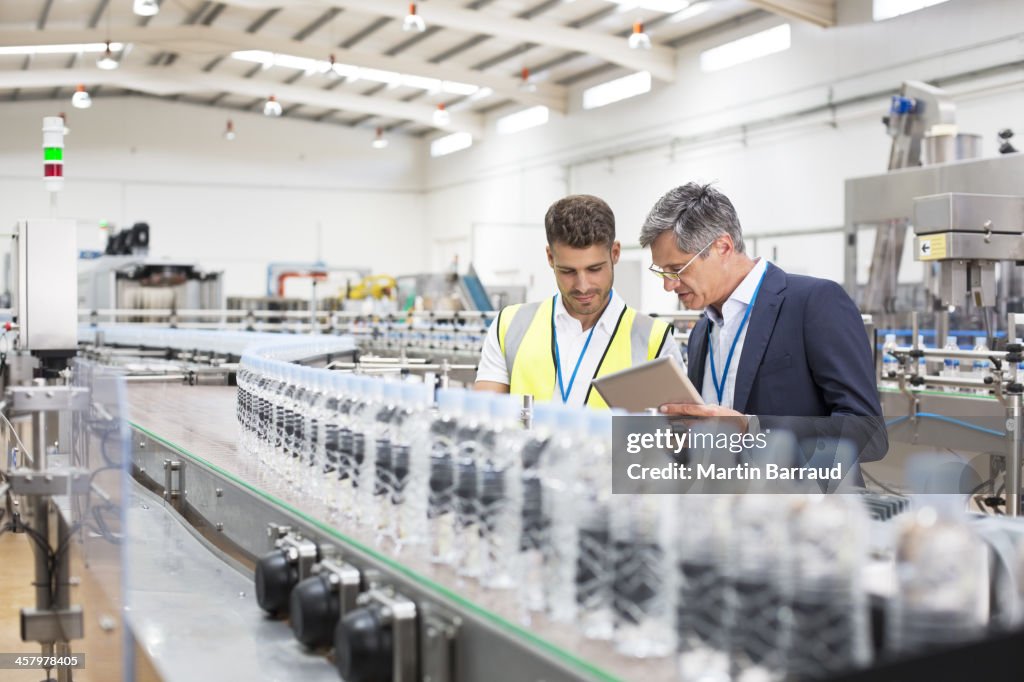 Supervisor and manager watching plastic bottles on conveyor belt