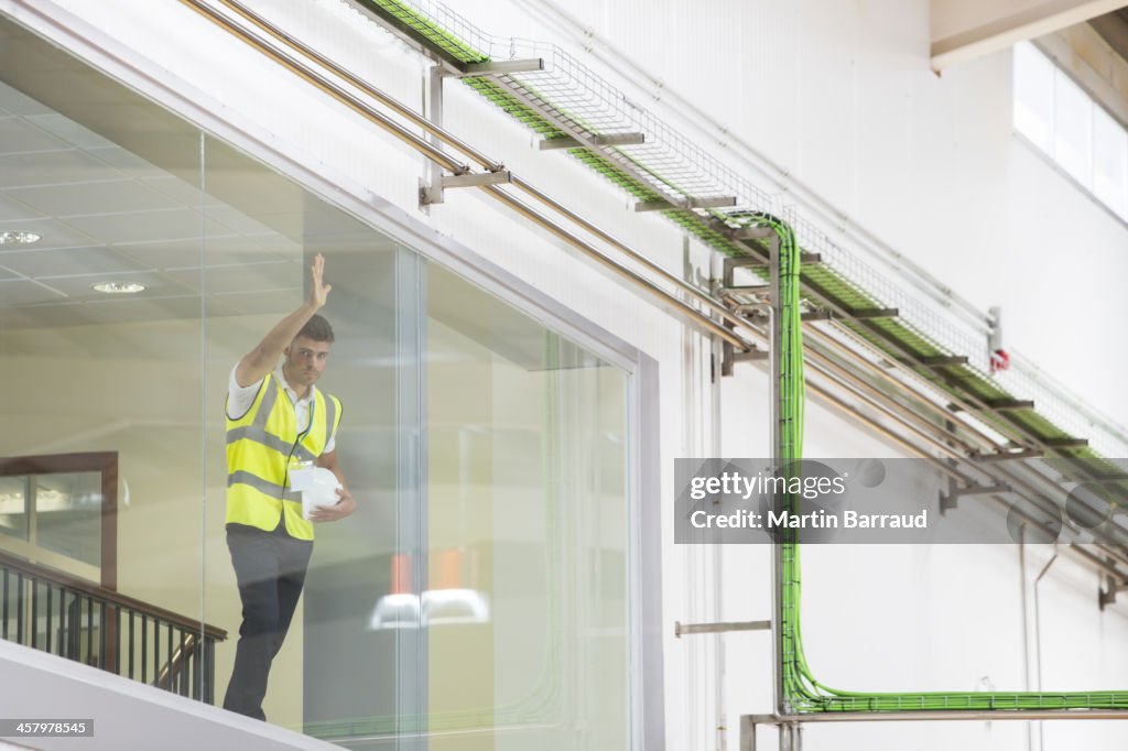 Worker leaning on observation window in factory