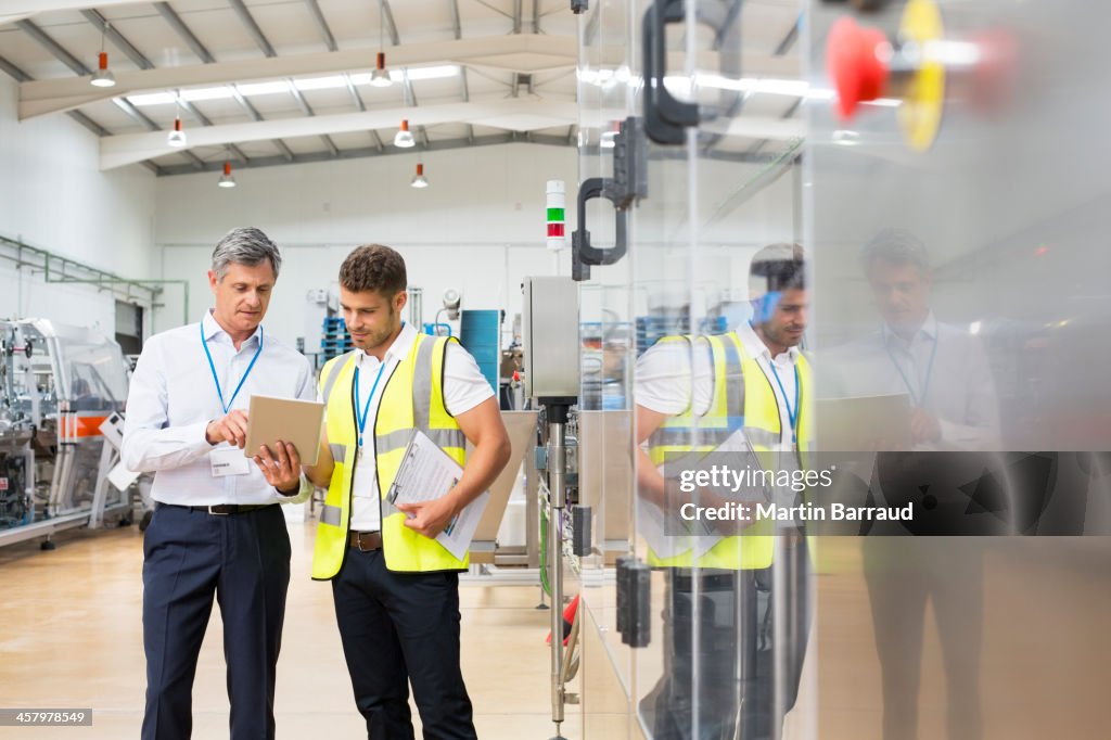 Supervisor y trabajador usando tableta digital en fábrica