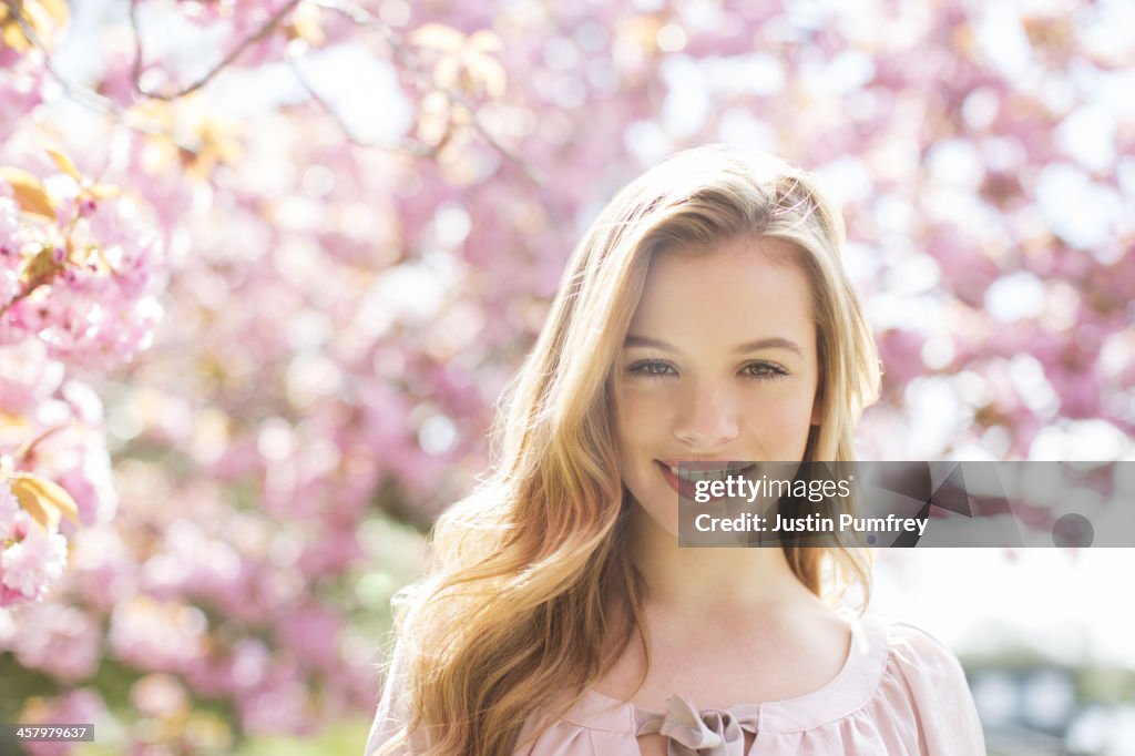 Woman smiling under tree with pink blossoms