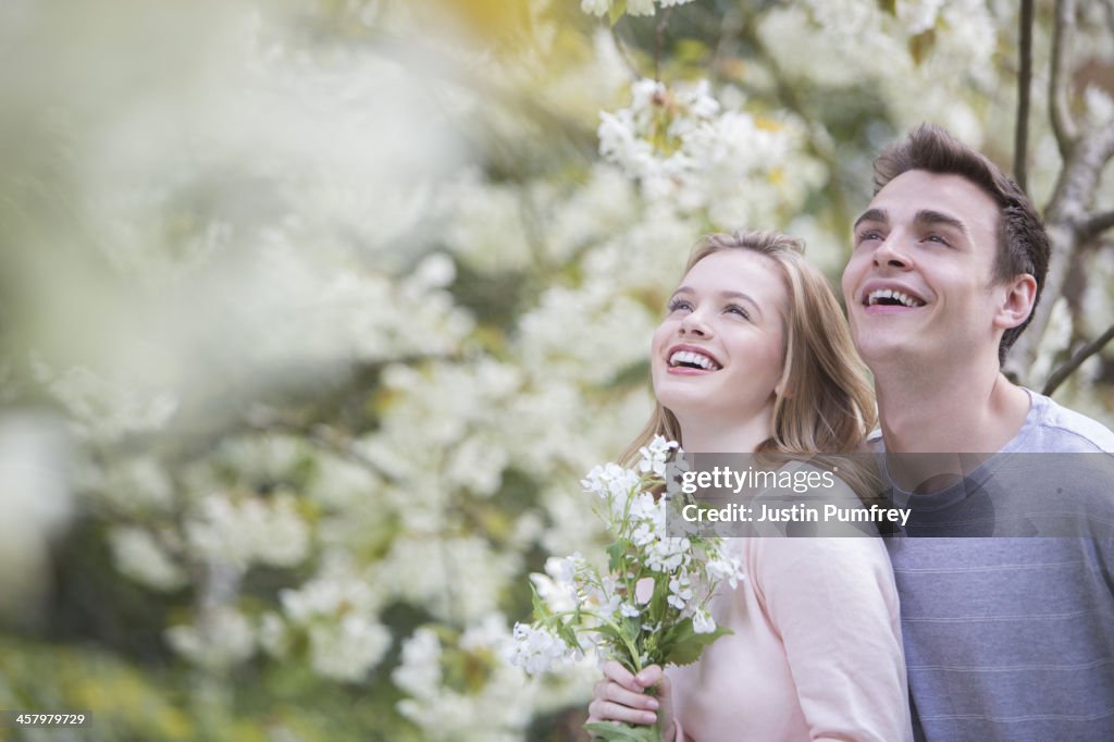 Couple smiling under tree with white blossoms