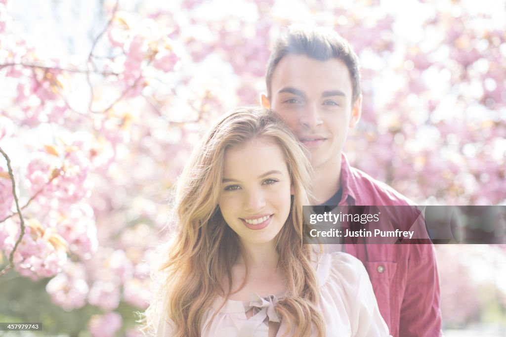 Couple hugging under tree with pink blossoms