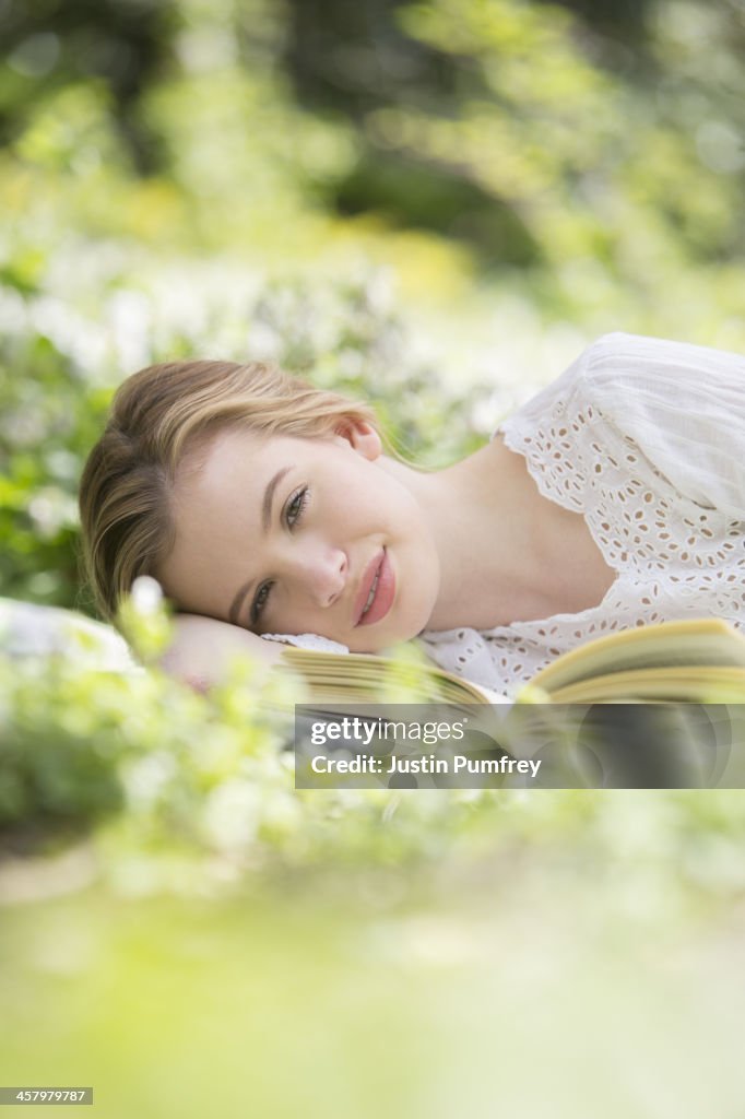 Woman relaxing in grass with book