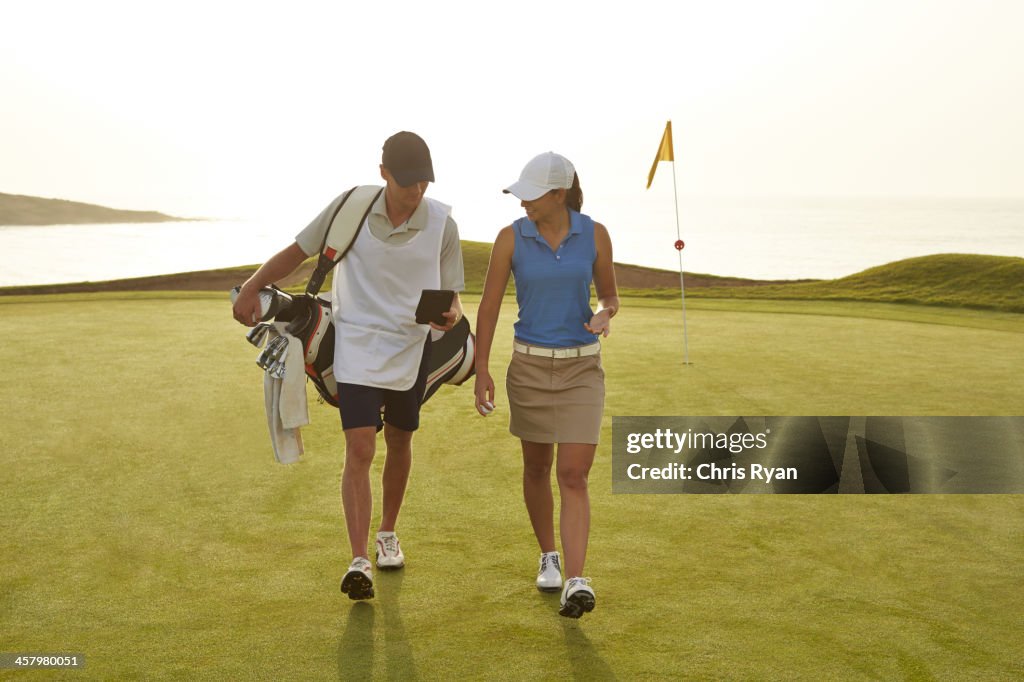 Jogador de golfe e o caddy a caminhar no campo de golfe