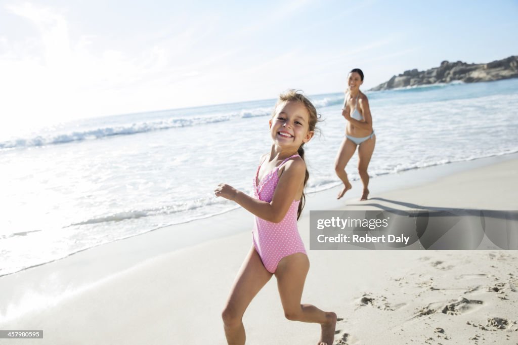 Mother and daughter running on beach