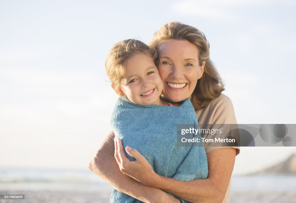Grandmother and granddaughter hugging on beach