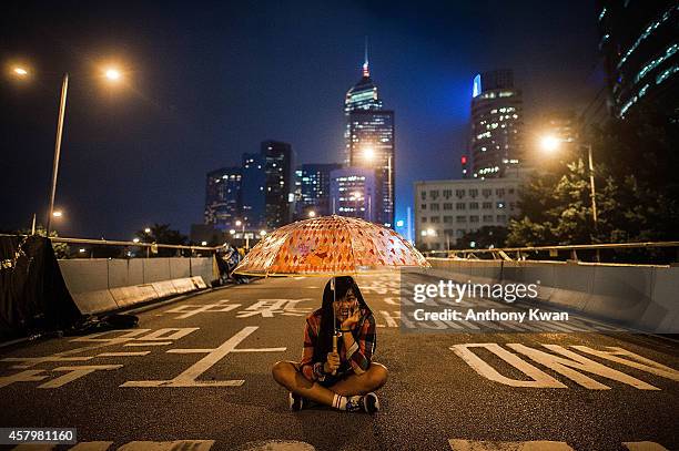 Pro-democracy protester holds umbrella in the air outside of Hong Kong Government Complex as they mark one month since police used tear gas in an...