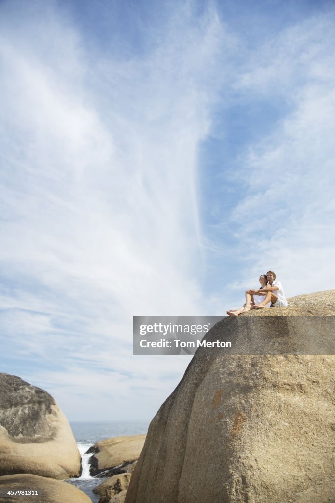 Couple sitting on rock formation on beach