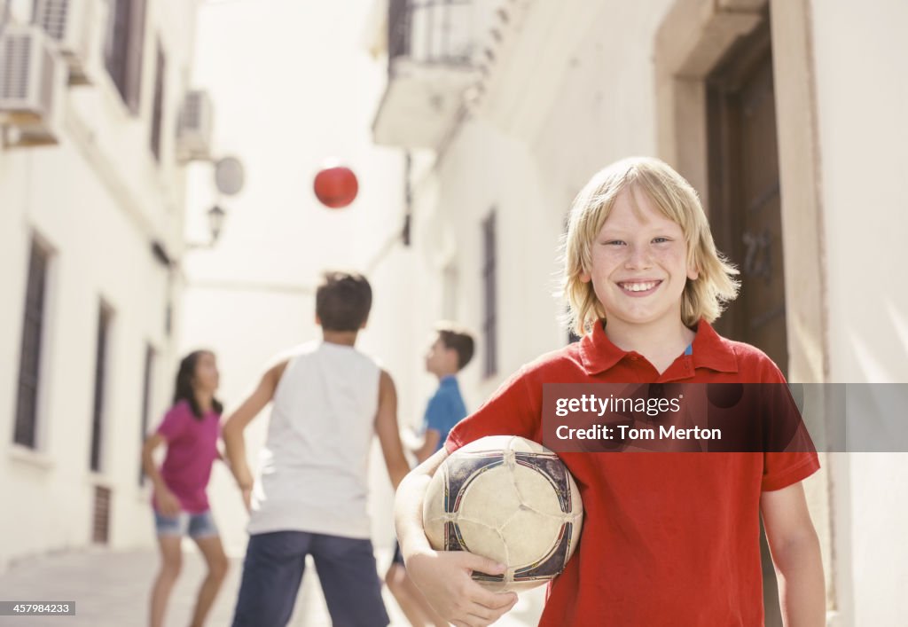 Menino segurando Bola de Futebol no Beco