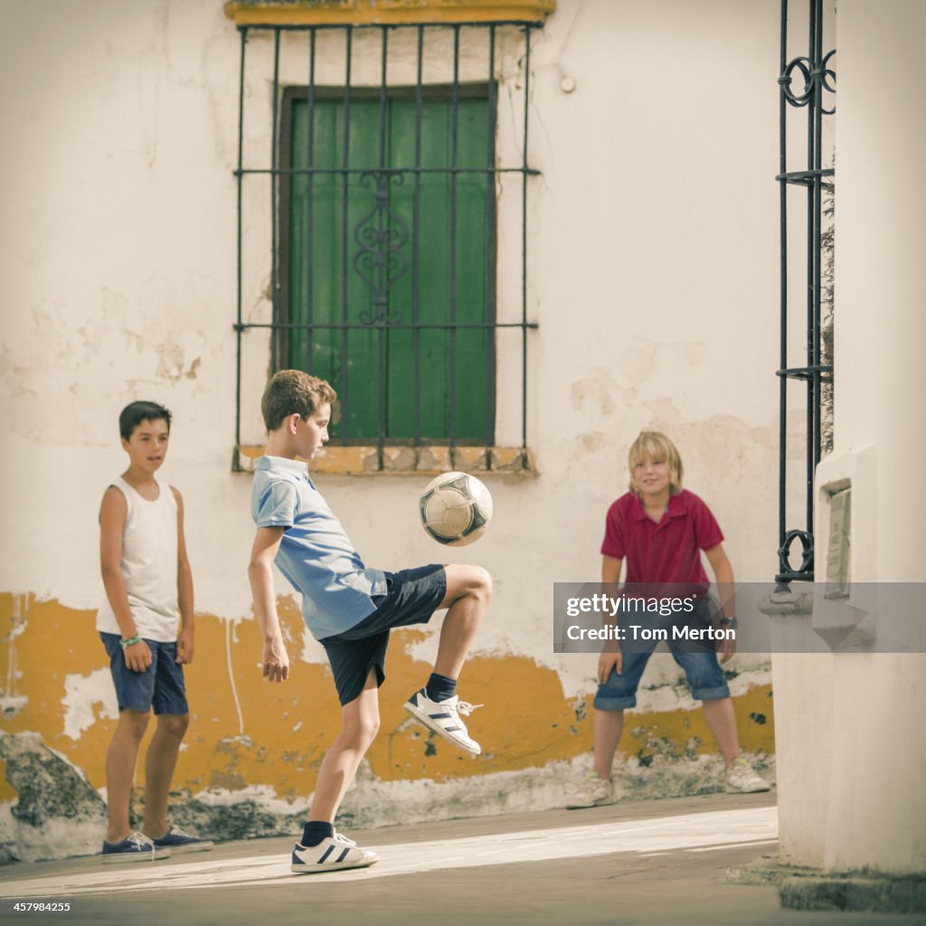 Children playing with soccer ball in alley